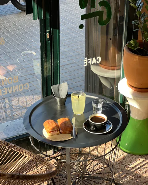 Mesa junto a la puerta con un café, algo de comer y una limonada